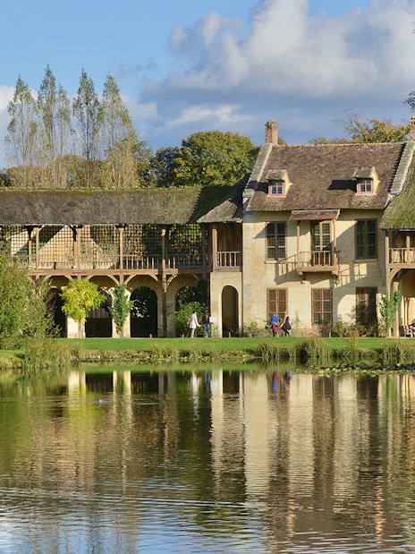 Tourists walking by the lake at Versailles Palace, France.