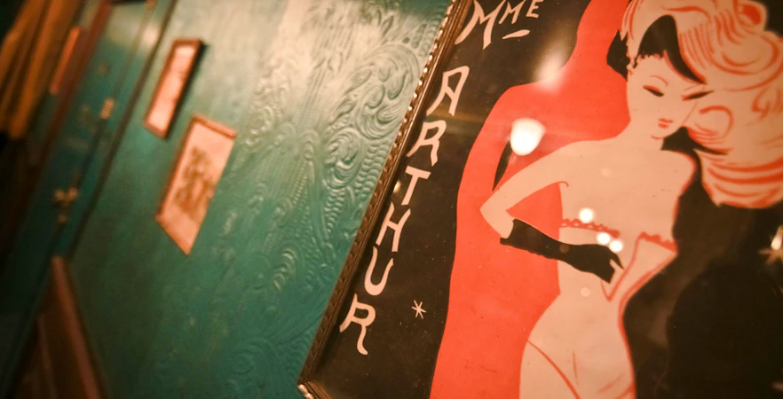 Madame Arthur cabaret show poster on a textured teal wall.