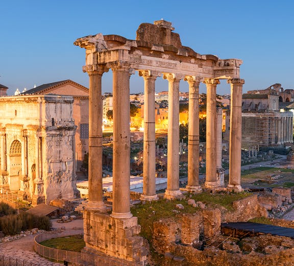 Roman Forum ruins with ancient columns at sunset in Rome, Italy.