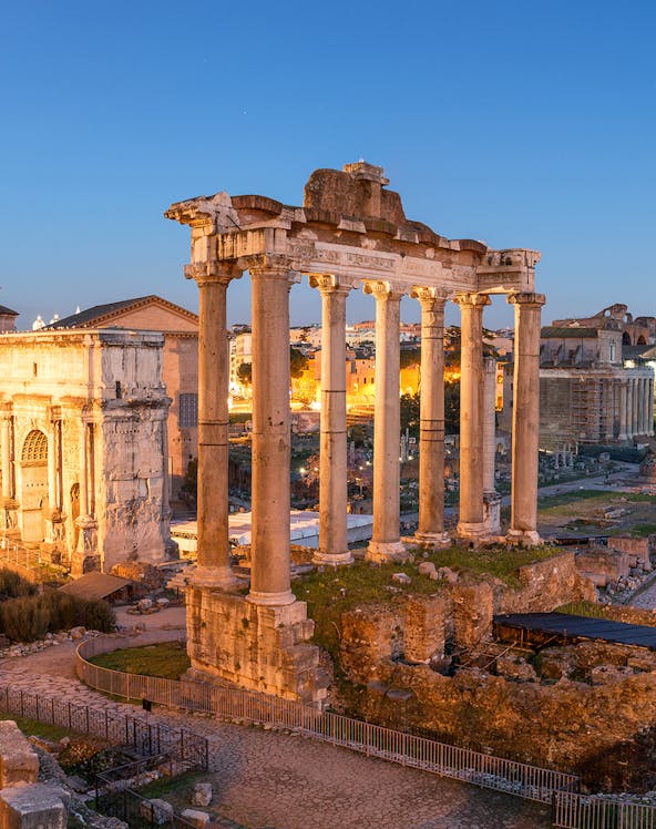 Roman Forum ruins with ancient columns at sunset in Rome, Italy.
