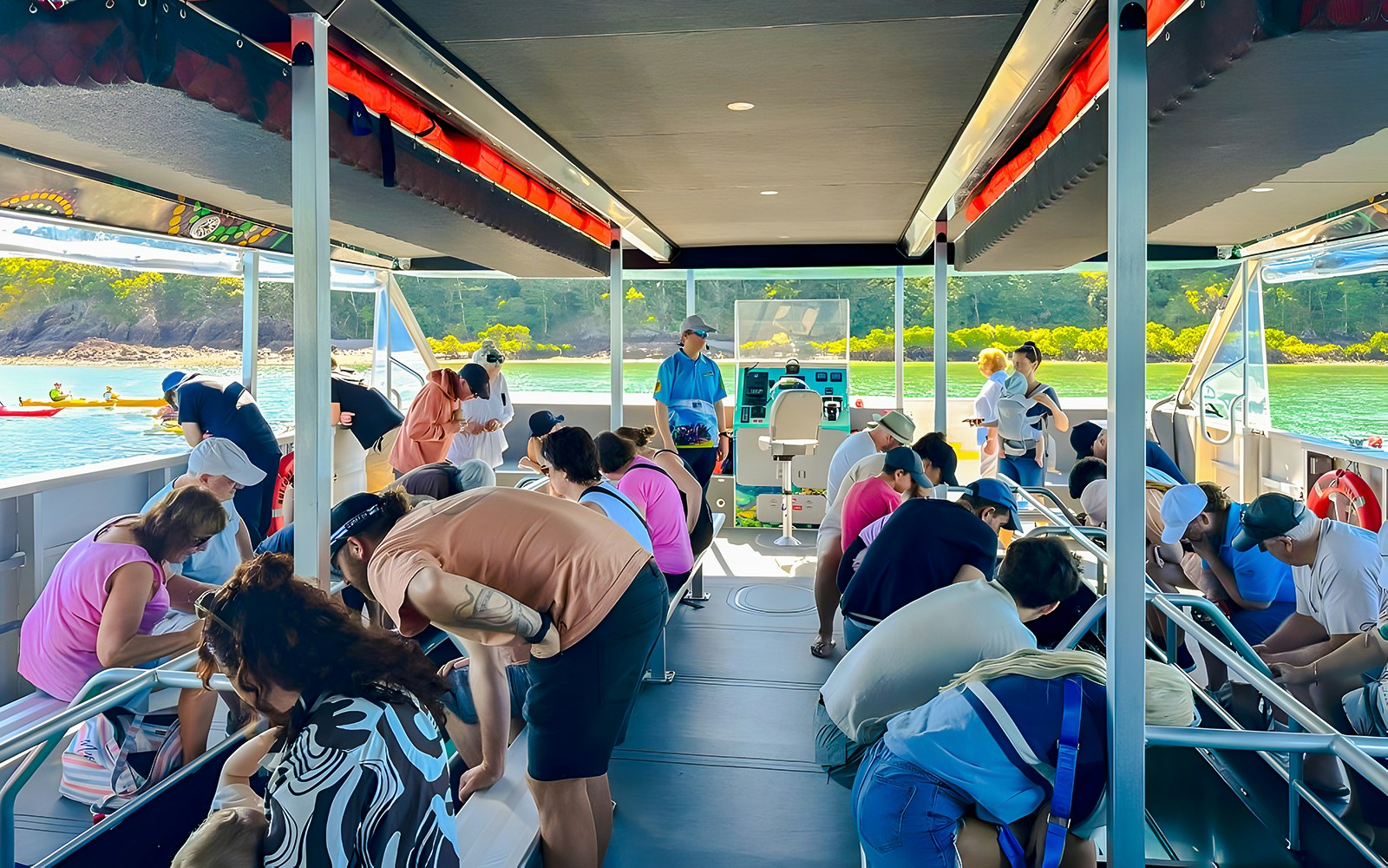 People observing marine life through glass floor on Airlie Beach Glass Bottom Boat tour.