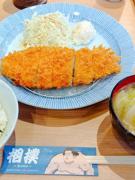 Sumo show lunch with rice, miso soup, and breaded cutlet on a plate.