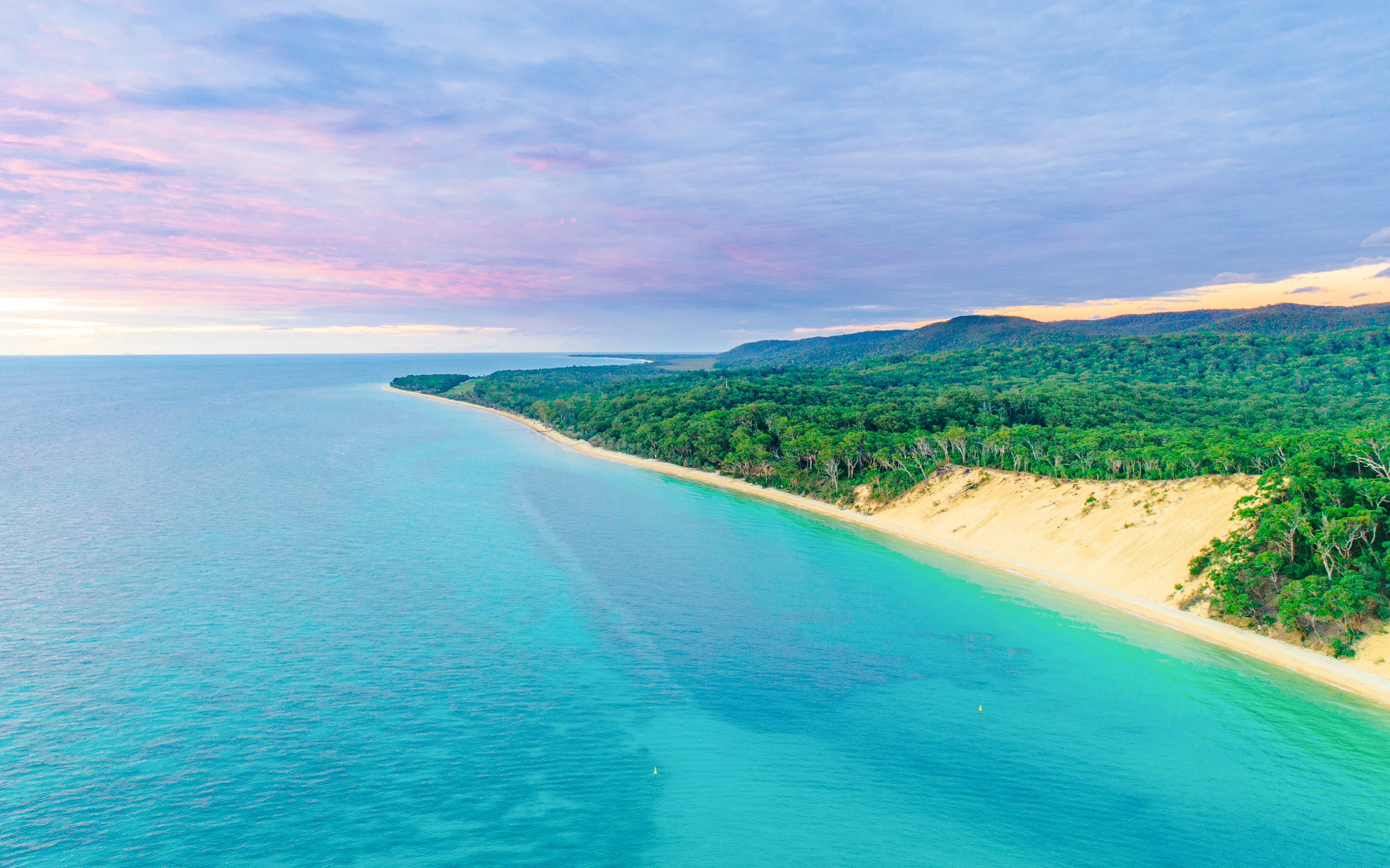 Aerial view of Moreton Island coastline with turquoise waters and lush greenery, Queensland, Australia.