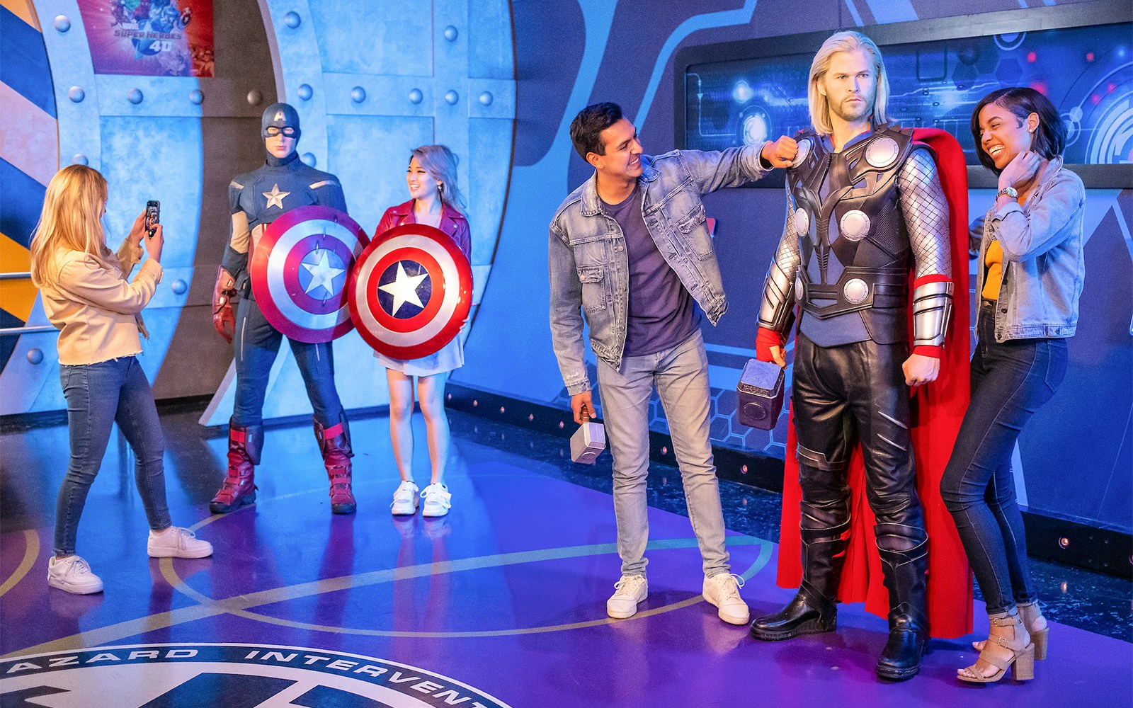 Visitors interacting with Marvel superhero figures at Madame Tussauds, New York.