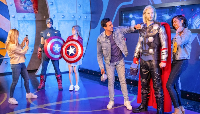 Visitors interacting with Marvel superhero figures at Madame Tussauds, New York.