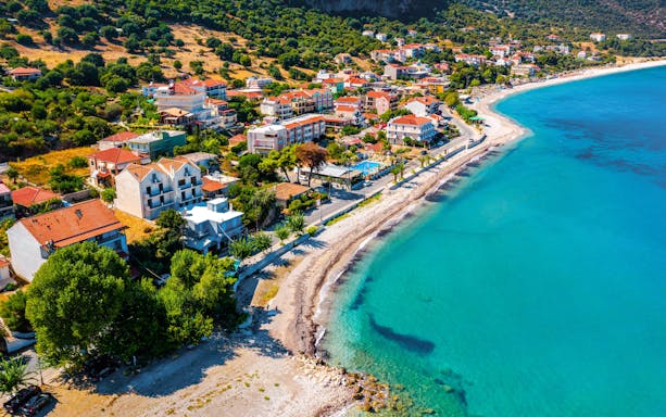 Aerial view of Poros coastline on Kefalonia island, Greece, with turquoise waters and coastal village.