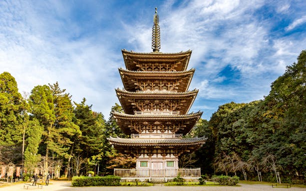 Five-story pagoda at Daigoji Temple, Kyoto, surrounded by trees under a blue sky.
