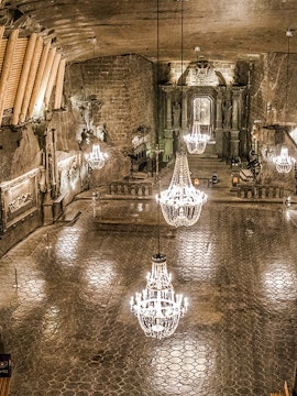 Wieliczka Salt Mine chamber with chandeliers and carved walls.