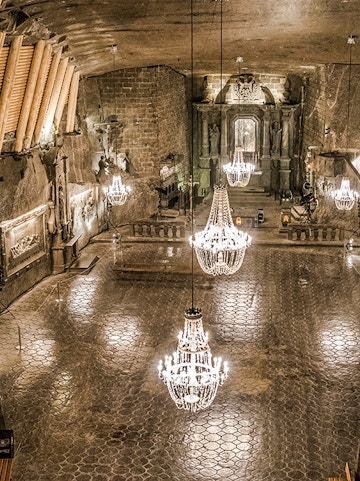 Wieliczka Salt Mine chamber with chandeliers and carved walls.