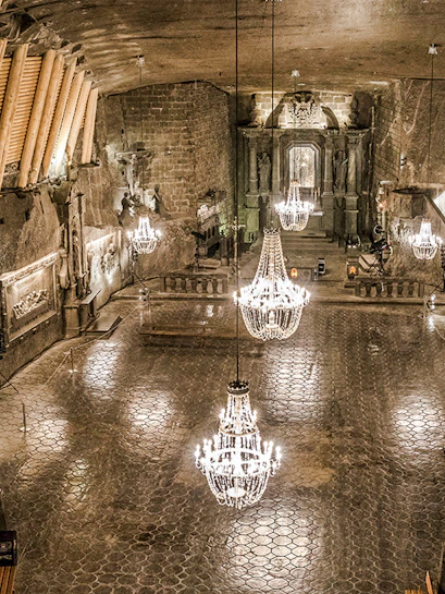 Wieliczka Salt Mine chamber with chandeliers and carved walls.