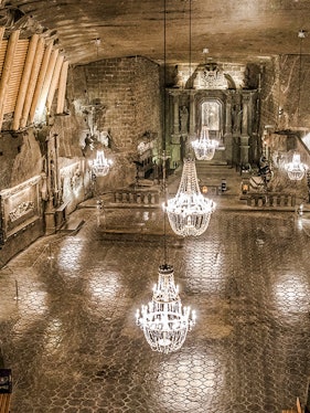Wieliczka Salt Mine chamber with chandeliers and carved walls.