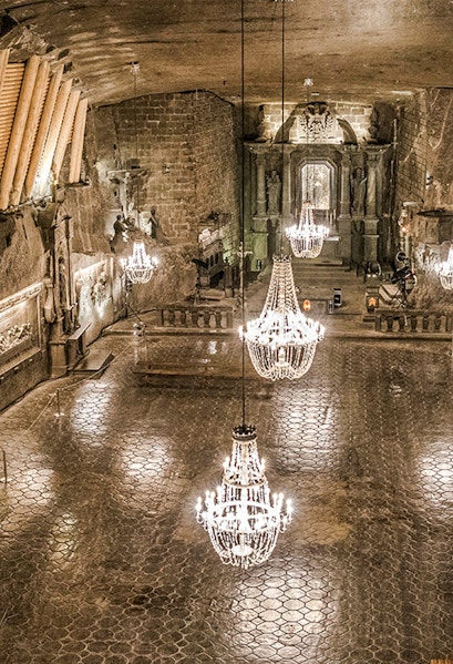 Wieliczka Salt Mine chamber with chandeliers and carved walls.