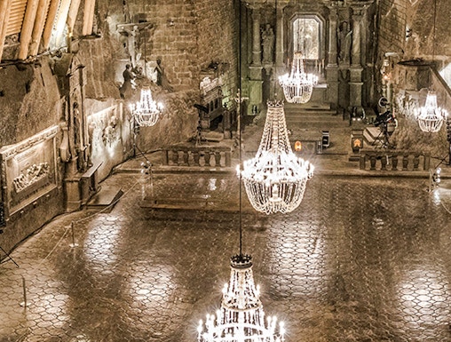 Wieliczka Salt Mine chamber with chandeliers and carved walls.