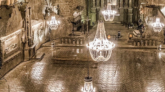 Wieliczka Salt Mine chamber with chandeliers and carved walls.