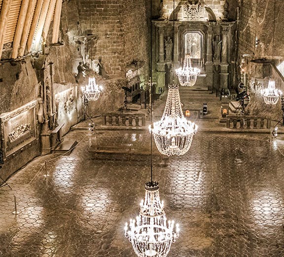 Wieliczka Salt Mine chamber with chandeliers and carved walls.