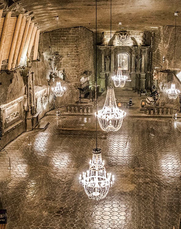 Wieliczka Salt Mine chamber with chandeliers and carved walls.