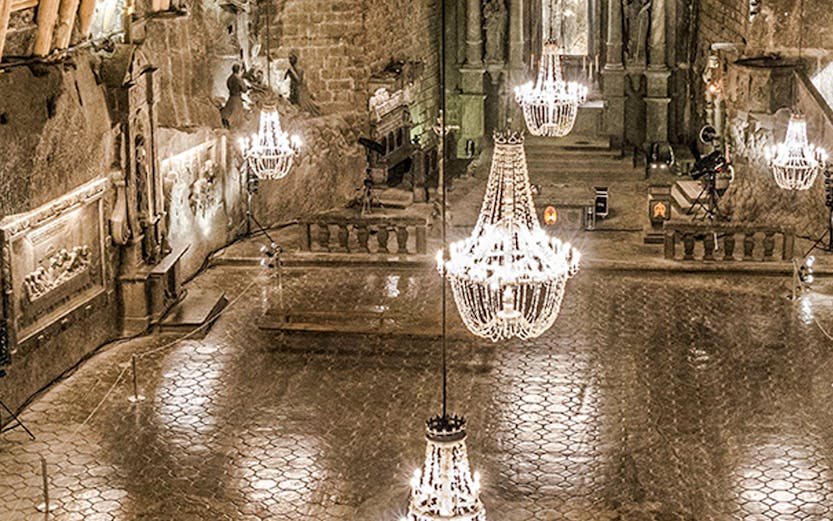 Wieliczka Salt Mine chamber with chandeliers and carved walls.