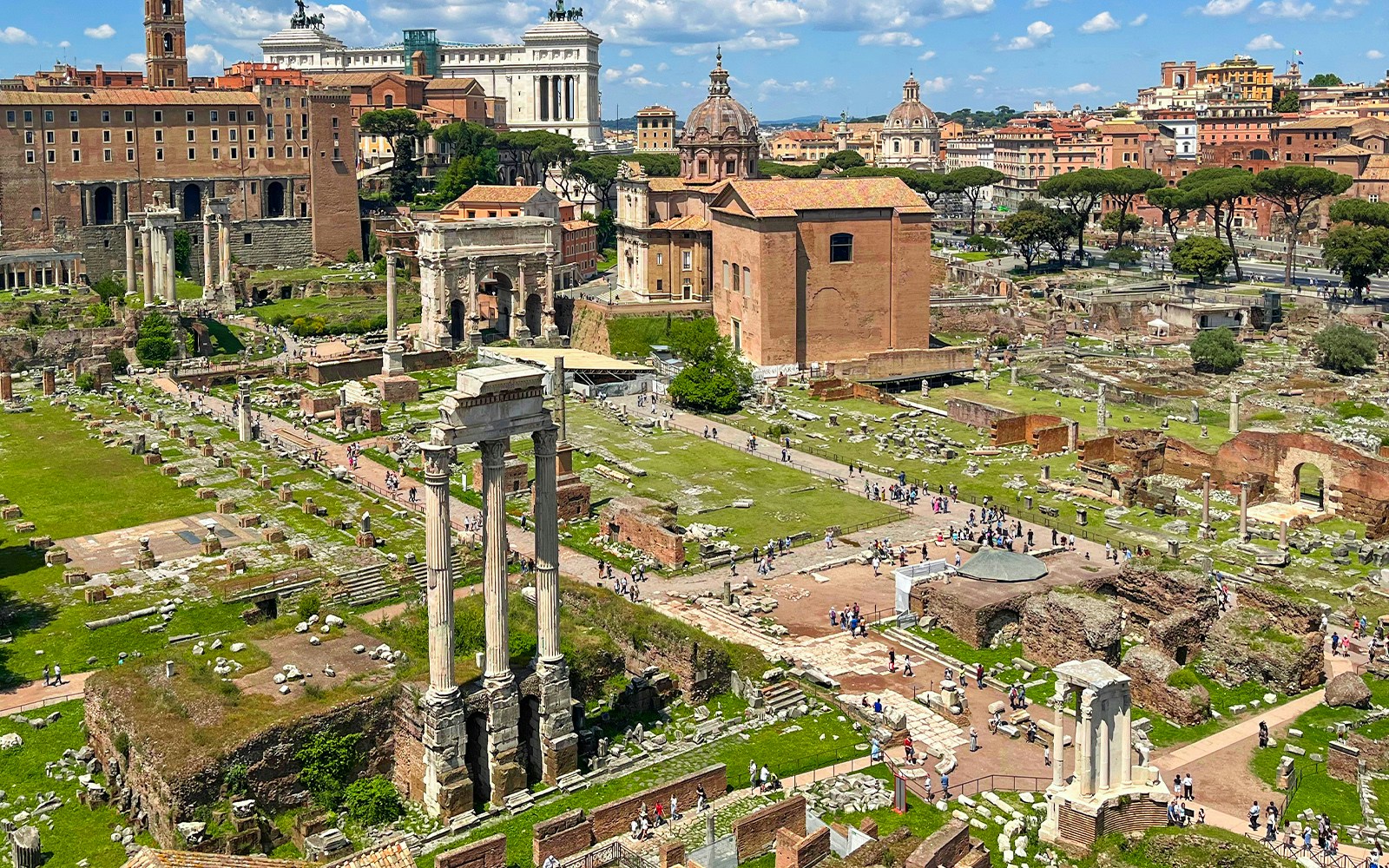 Ancient ruins along Via Sacra's pathway in the Roman Forum, Rome, with historic structures and tourists.