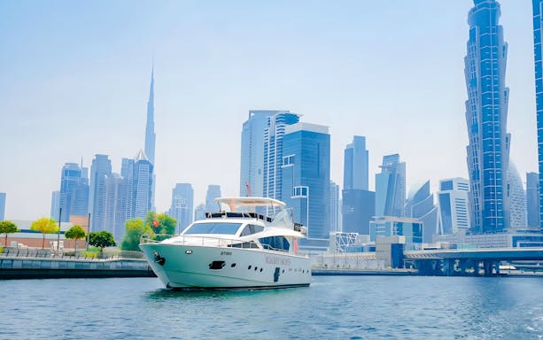 Yacht cruising through Dubai canal with Burj Khalifa and skyline in view.