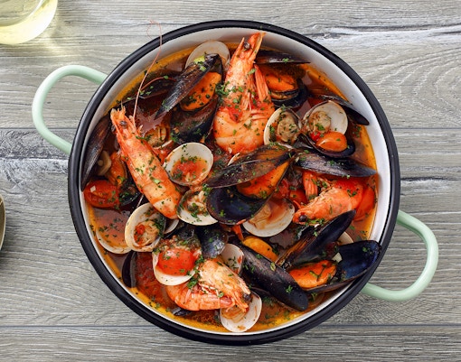 Zuppa di Cozze with tomato sauce on gray table background.
