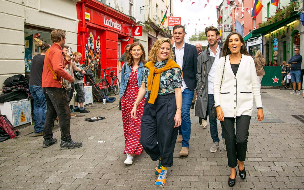 Tour guide leading a group through a lively street with musicians performing.