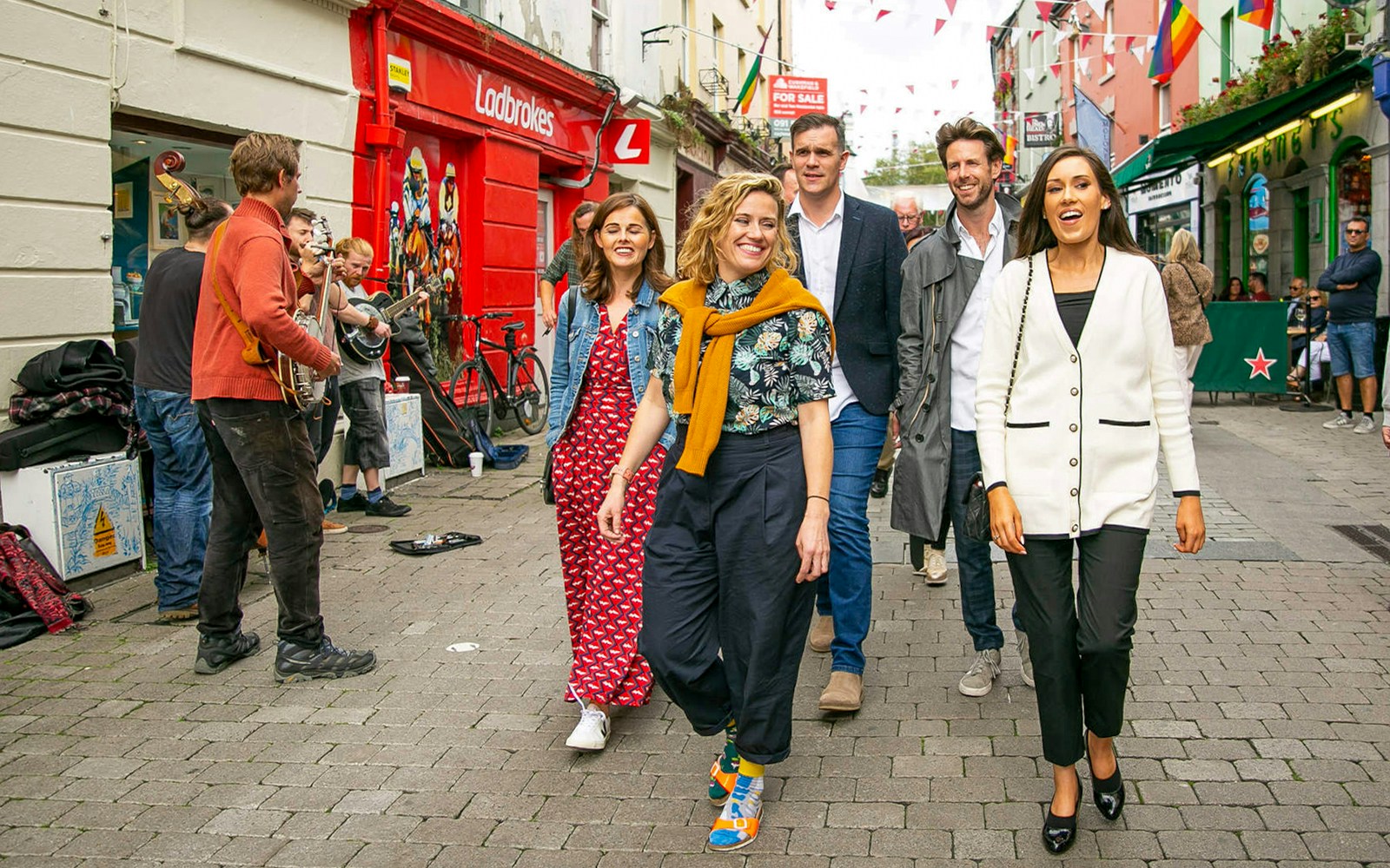 Tour guide leading a group through a lively street with musicians performing.