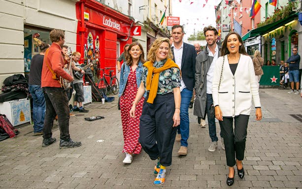 Tour guide leading a group through a lively street with musicians performing.