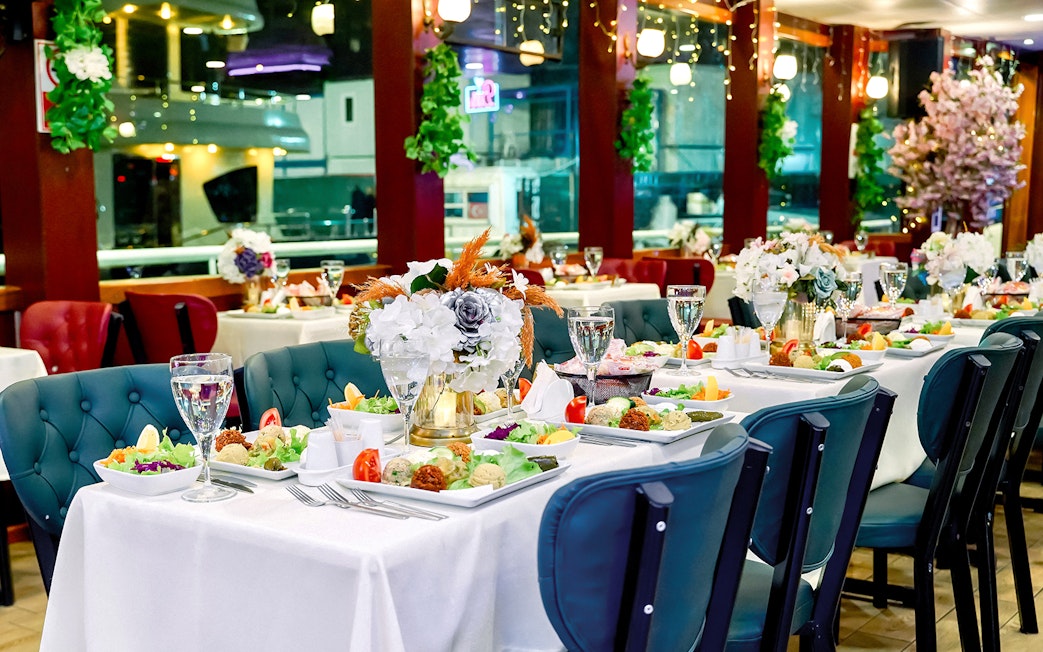 Table set for Turkish dinner on Bosphorus cruise with floral centerpieces and assorted dishes.