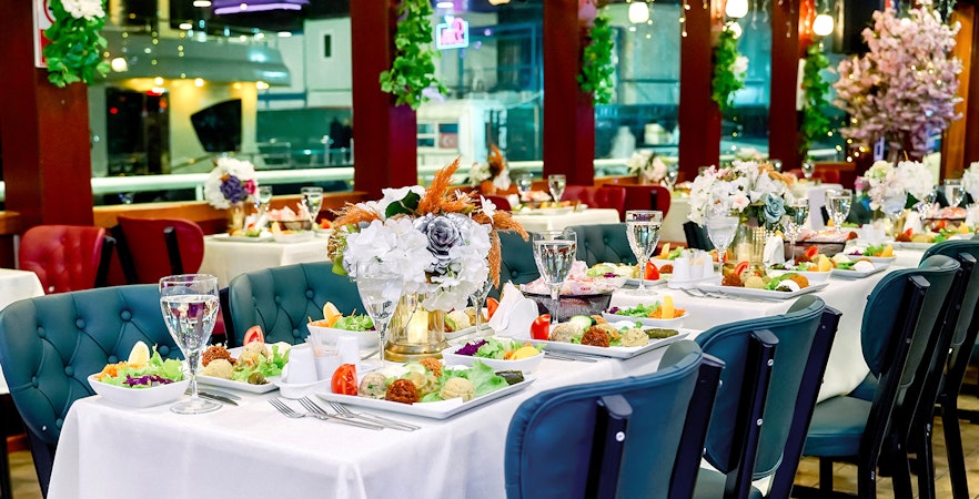 Table set for Turkish dinner on Bosphorus cruise with floral centerpieces and assorted dishes.