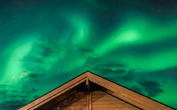 Aurora Borealis over lodge roof, Northern Lights Alaska.