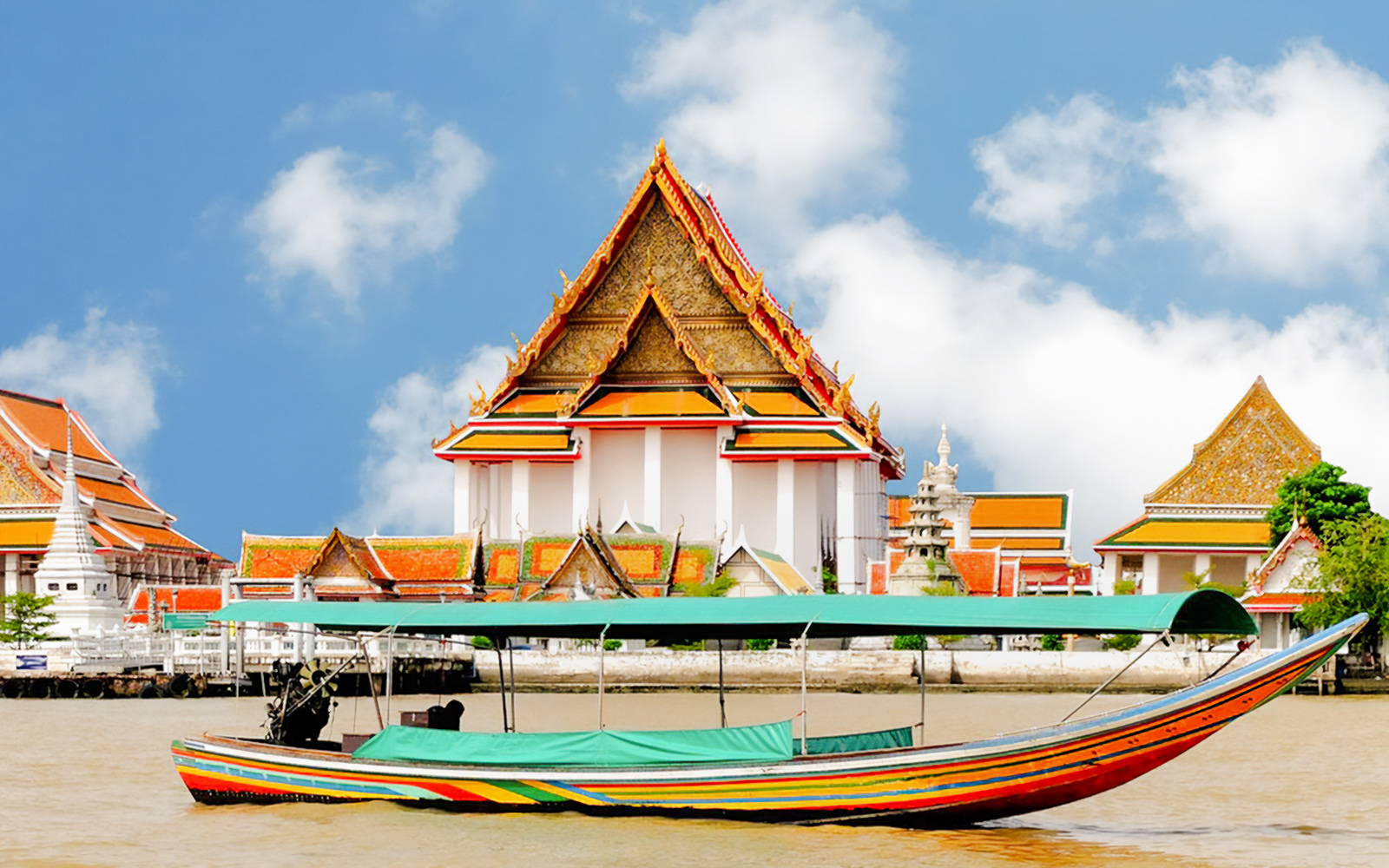 Long-tail boat on river with Wat Kalyanamit temple in the background, Bangkok, Thailand.