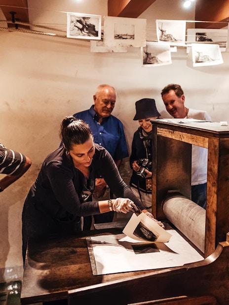 Guide demonstrating printmaking to visitors at Rembrandt House Museum.