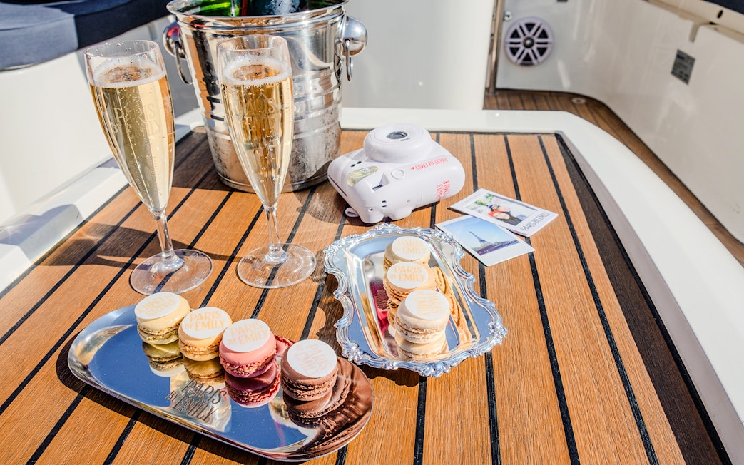 Champagne glasses and macarons on a table during The Official Emily in Paris Champagne Seine Cruise.