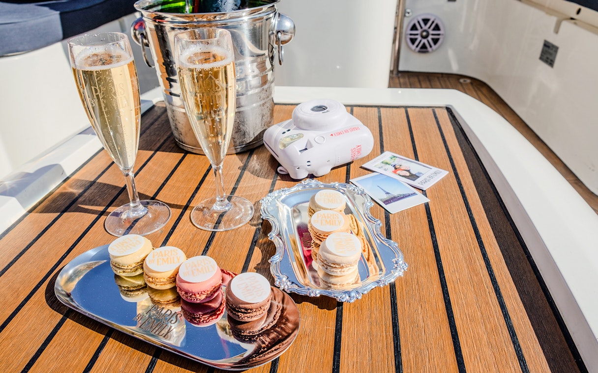 Champagne glasses and macarons on a table during The Official Emily in Paris Champagne Seine Cruise.