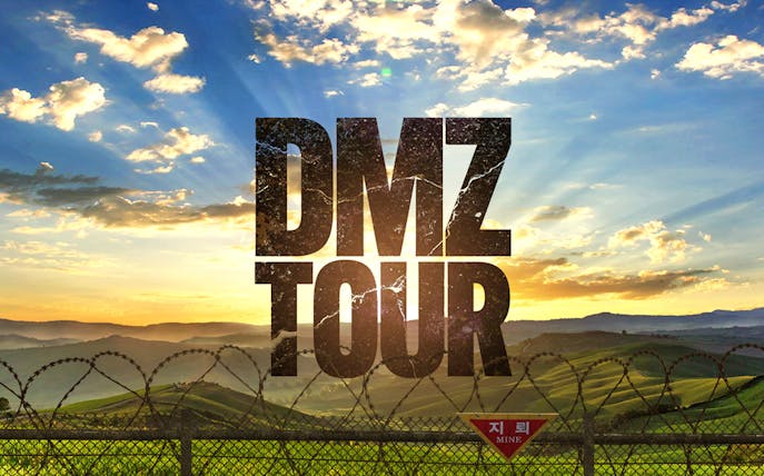 DMZ Tour text over barbed wire fence and scenic landscape at sunrise.