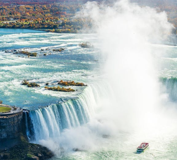 Niagara Falls with tour boat approaching, highlighting the "Journey Behind the Falls" experience.