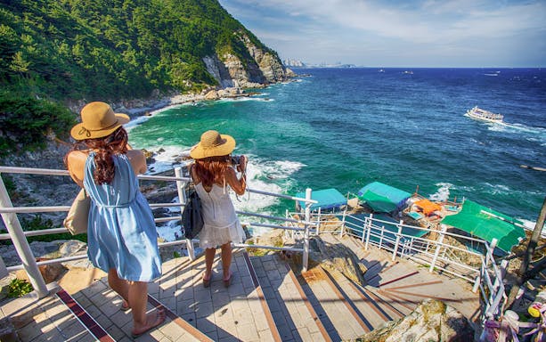 Women overlooking the ocean from a scenic viewpoint in Busan during a city tour.