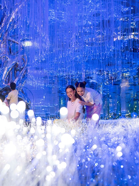 Visitors exploring the illuminated installations at AYA Universe.