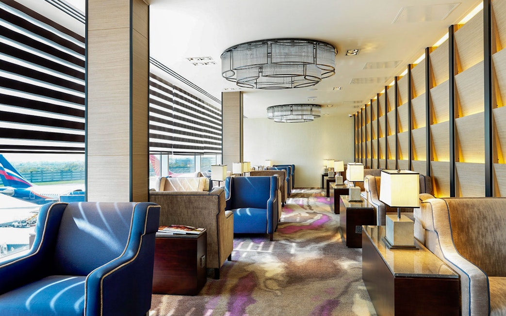 Heathrow Plaza Premium Lounge seating area with armchairs and tables near large windows.