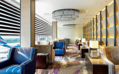 Heathrow Plaza Premium Lounge seating area with armchairs and tables near large windows.