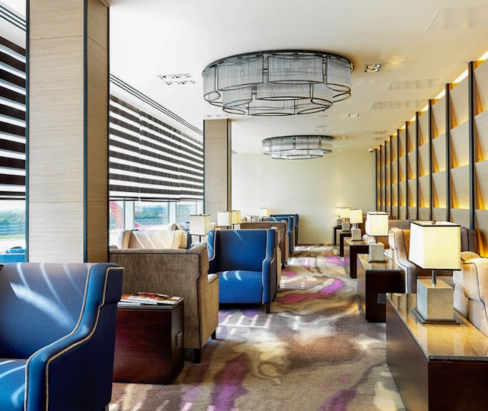 Heathrow Plaza Premium Lounge seating area with armchairs and tables near large windows.