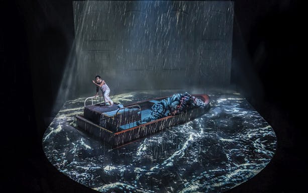 Stage scene from "Life of Pi" with a person on a boat in a stormy sea projection.