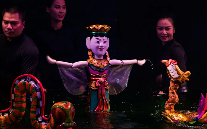 Large female puppet and colorful dragon puppets in water puppet show, Hanoi.