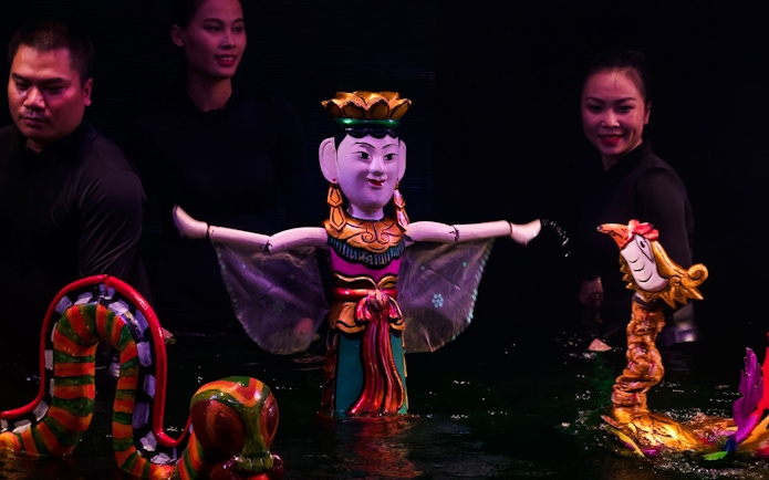 Large female puppet and colorful dragon puppets in water puppet show, Hanoi.