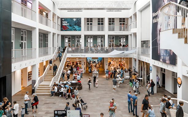 Interior of National Museum of Denmark with visitors, museum shop, and café.
