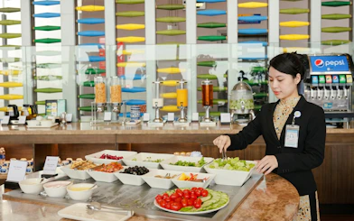 Buffet selection at SH Premium Lounge, Noi Bai International Airport, Hanoi, with staff serving salad.