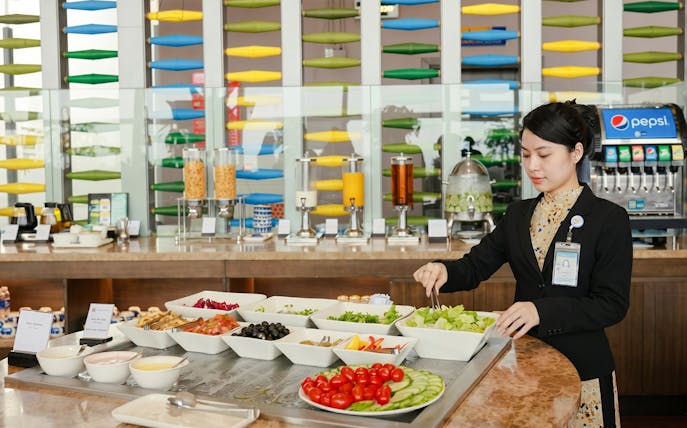 Buffet selection at SH Premium Lounge, Noi Bai International Airport, Hanoi, with staff serving salad.