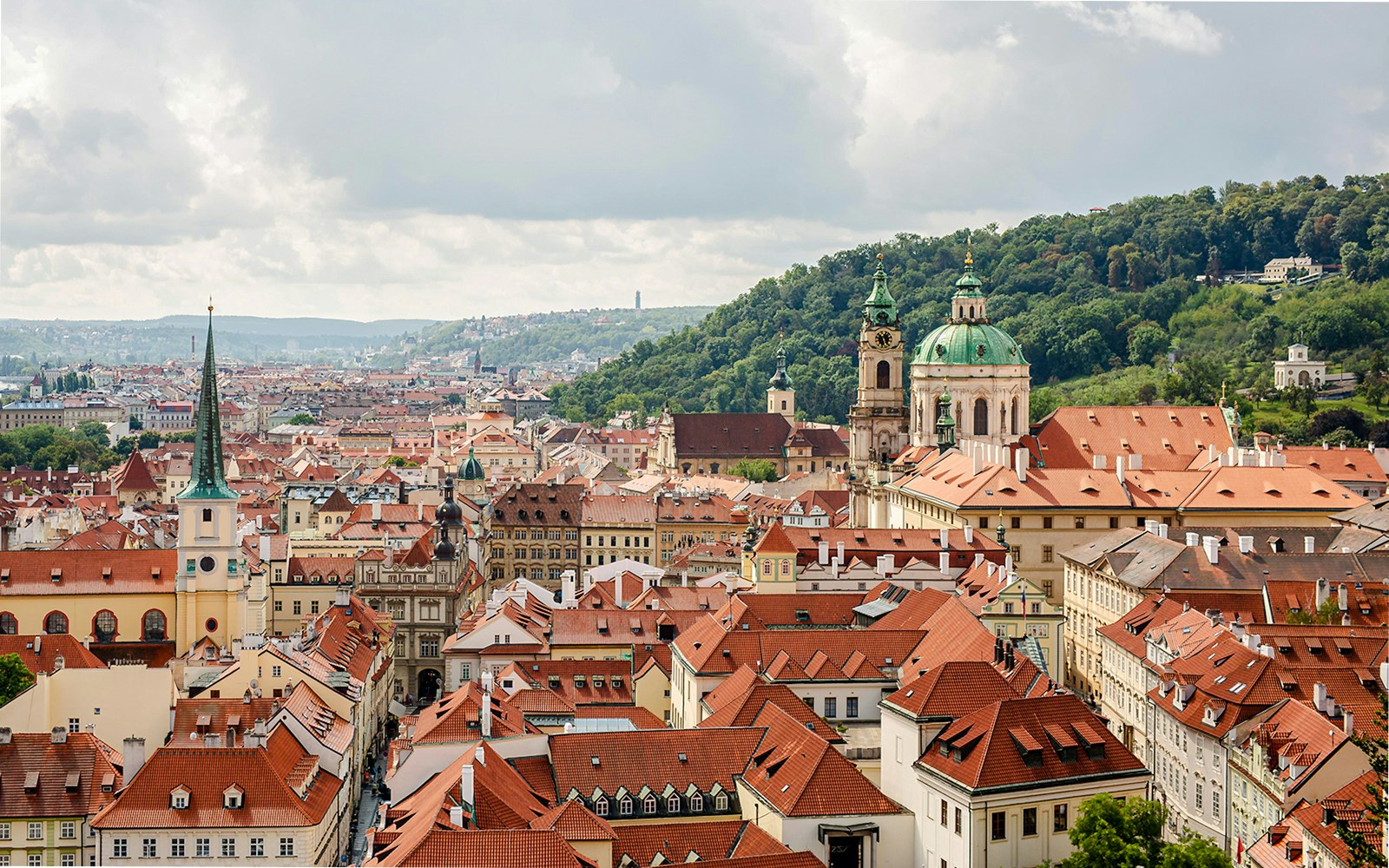 Prague skyline with red rooftops and St. Nicholas Church in Lesser Town, Prague.