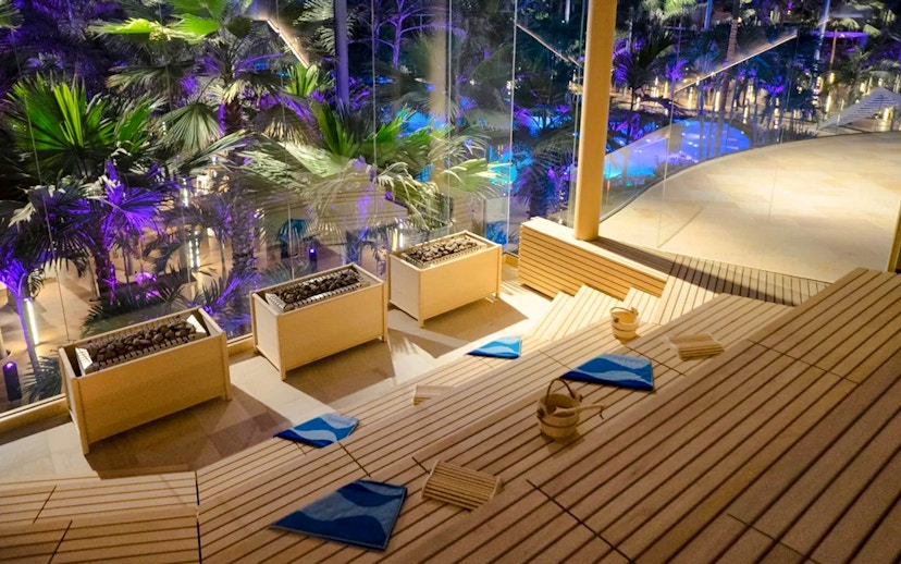 Therme Bucharest sauna interior with tropical plants and night lighting.