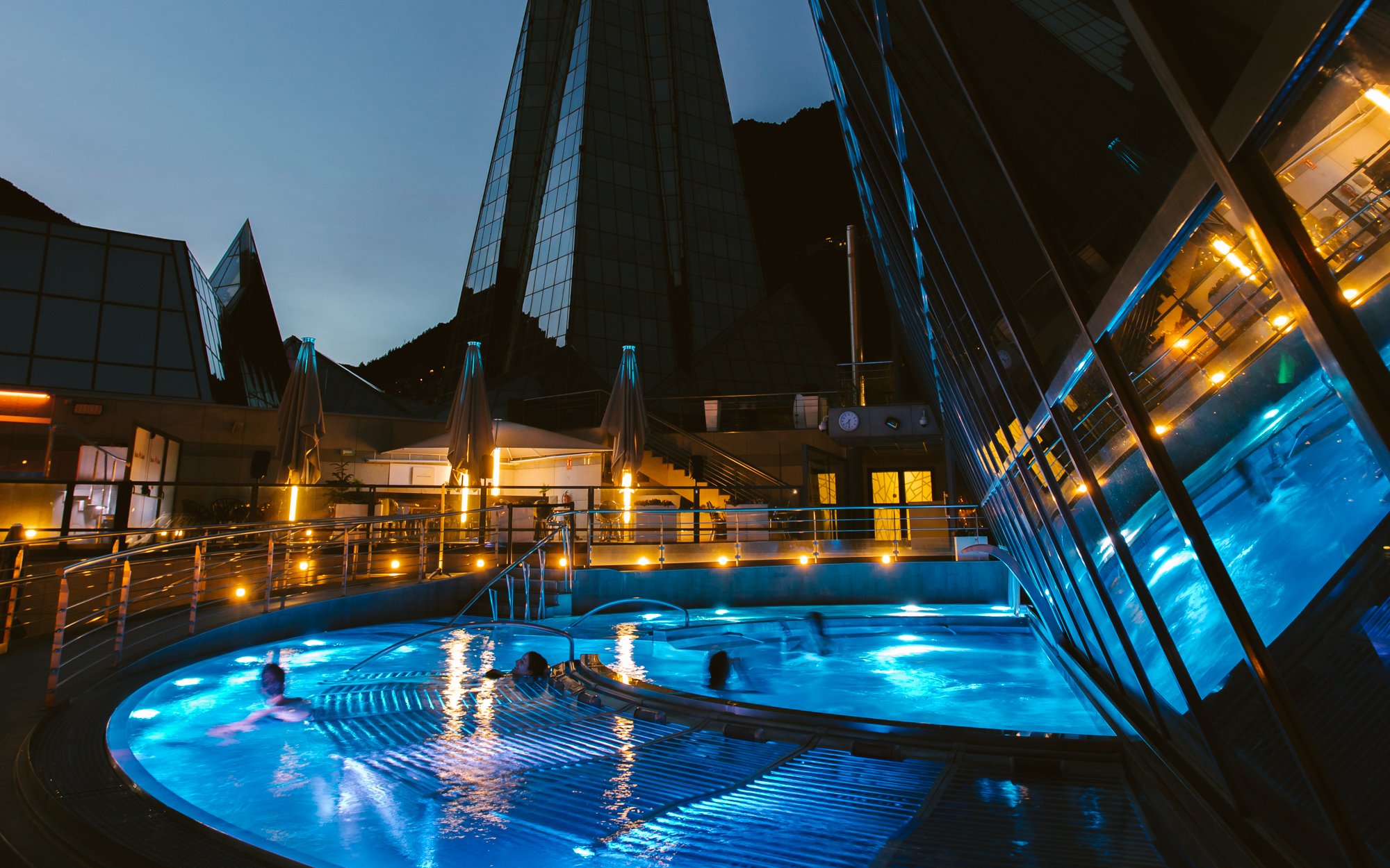 Outdoor lagoon at Caldea thermal spa illuminated at night with modern architecture.